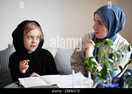 Mère portant le hijab aidant son à faire ses devoirs Banque D'Images