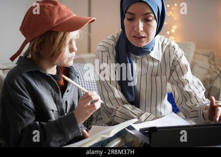 Mère portant le hijab aidant son à faire ses devoirs Banque D'Images