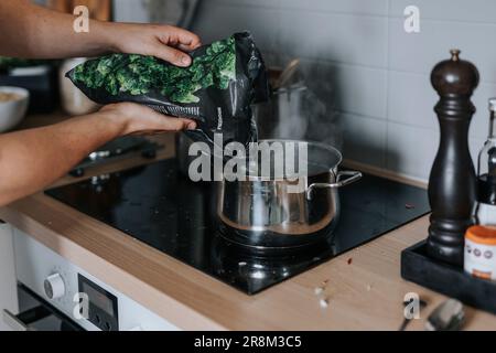Les mains de la femme mettent les légumes dans une casserole Banque D'Images