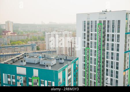 fumée de smog dans la ville. bâtiments élevés, bâtiments à panneaux, tour de toit, rue, route, montagnes, complexe résidentiel dans un nuage de fumée. problème écologique. Banque D'Images