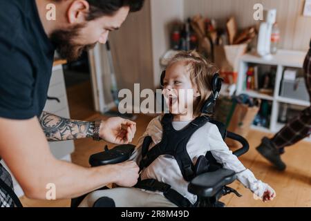 Père prenant soin d'un enfant handicapé heureux en fauteuil roulant Banque D'Images