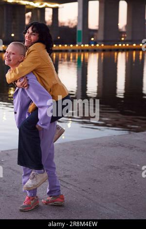Jeune femme donnant à un ami ou une petite amie promenade en porcgyback, homme prenant la photo Banque D'Images