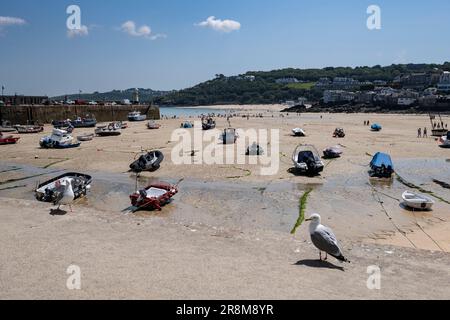 Le port de St Ives en Cornouailles avec la marée et de petits bateaux reposant sur le sable. Les vacanciers peuvent profiter au maximum du temps chaud. Banque D'Images