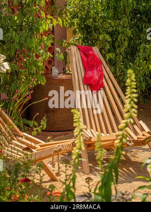 Chaises longues pliantes en bois dans un petit jardin à l'occasion d'un spectacle du jardin britannique. Banque D'Images