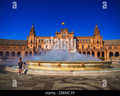 Un groupe de personnes se promène tranquillement près d'une majestueuse fontaine et d'un bâtiment à Madrid, en Espagne, au coucher du soleil Banque D'Images