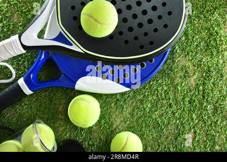 Deux raquettes de tennis de paddle et une boîte de balles sur l'herbe artificielle. Vue de dessus. Banque D'Images