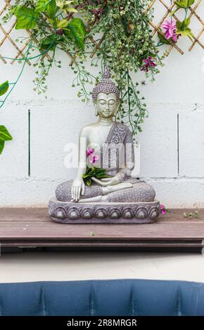 Une verticale d'une statue de Bouddha entourée de fleurs Banque D'Images