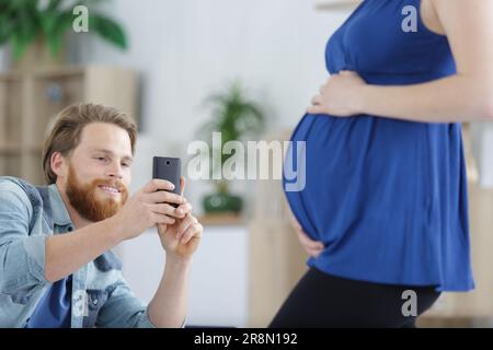père prenant des photos de sa femme enceinte Banque D'Images