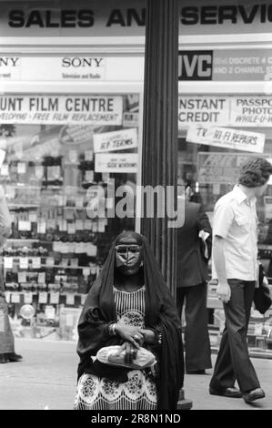 Arab Woman Earls court Londres 1970s Royaume-Uni. Les habitants du Moyen-Orient sont venus en Grande-Bretagne pour des soins de santé subventionnés dans les cliniques Harley Street. Ils ont principalement séjourné dans des hôtels bon marché à Earls court. Une femme arabe portant un masque Battoulah qui a généralement indiqué qu'elle était mariée. Earls court, Londres, Angleterre vers 1977 70s HOMER SYKES Banque D'Images
