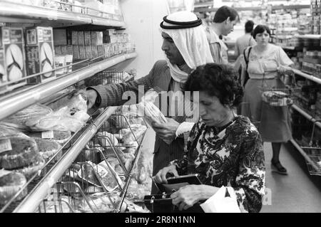 Pauvres Arabes à Londres Food Shopping 1970s Royaume-Uni . À la fin de l'année 1970s, les gouvernements du Moyen-Orient ont fourni des soins de santé à leurs ressortissants à Londres, beaucoup ont séjourné dans un hébergement pas cher dans le quartier de Earls court. Un couple épicerie shopping l'homme achète Pita est un pain plat. Earls court, Londres, Angleterre vers 1977 70s HOMER SYKES Banque D'Images