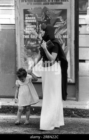 La mère musulmane et l'enfant pauvres Arabes à Londres 1970s. Les habitants du Moyen-Orient sont venus en Grande-Bretagne pour des soins de santé subventionnés dans les cliniques Harley Street. Ils ont principalement séjourné dans des hôtels bon marché à Earls court. Mère et fille. L'affiche du film est pour le Spy qui m'a aimée, en regardant Roger Moore comme James Bond. Earls court, Londres, Angleterre vers 1977 70s UK HOMER SYKES Banque D'Images