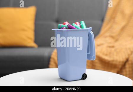 Mini-bac de recyclage avec différents types de piles sur table blanche à l'intérieur Banque D'Images