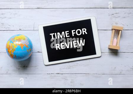 Vue de dessus du globe, de l'horloge de sable et de la tablette écrit avec le temps pour la revue sur fond de bois. Banque D'Images