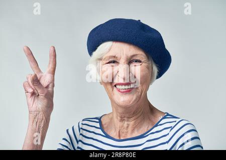 Femme française joyeuse montrant deux doigts comme symbole de salutation Banque D'Images