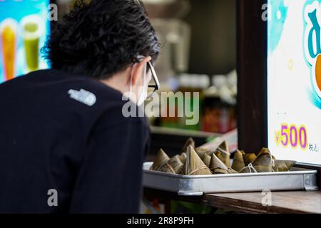 Yokohama, Japon. 22nd juin 2023. Un touriste achète Zongzi, un boulonnage en forme de pyramide fait de riz gluant enveloppé de feuilles de bambou ou de roseau, à l'occasion du festival de bateau-dragon dans le quartier chinois de Yokohama, Japon, 22 juin 2023. Credit: Zhang Xiaoyu/Xinhua/Alay Live News Banque D'Images