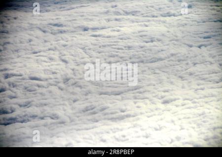 Vue aérienne de nuages blancs et moelleux contre un ciel bleu clair, vue à travers une fenêtre d'avion Banque D'Images