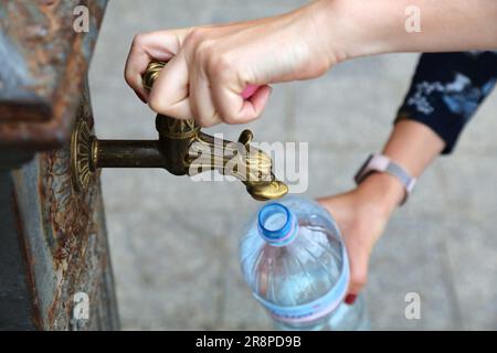 Remplissage de la bouteille en plastique pour animaux de compagnie à partir du robinet d'eau public à Alghero, Italie. Robinet municipal d'eau potable - tourisme durable. Banque D'Images