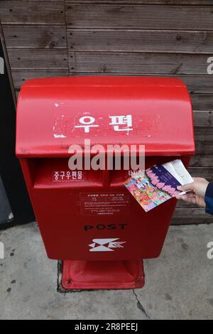 SÉOUL, CORÉE DU SUD - 7 AVRIL 2023 : personne envoyant des cartes postales dans la boîte aux lettres publique de Korea Post, le service postal national de Corée du Sud. Banque D'Images