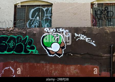 Un mur urbain orné de graffiti coloré situé à côté d'un bâtiment traditionnel en brique Banque D'Images