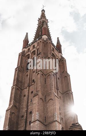 Sous un angle bas, la majestueuse tour de la cathédrale de Brugge s'étend vers le ciel, commandant l'attention et la beauté intemporelle. Banque D'Images