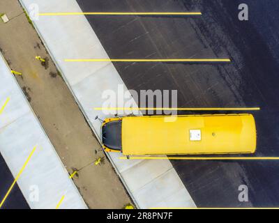 Vue aérienne d'un seul, un, parking d'autobus scolaire américain jaune dans un parking d'autobus avec surface en béton et en asphalte. Banque D'Images