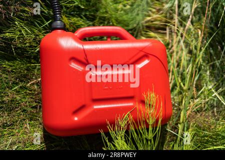 Réservoir en plastique rouge au milieu de l'herbe verte. Problèmes sur la route avec le carburant pour la voiture. Photo de haute qualité Banque D'Images