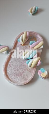 Image d'un petit plateau en céramique blanc rempli de guimauves roses et blanches sur fond blanc Banque D'Images