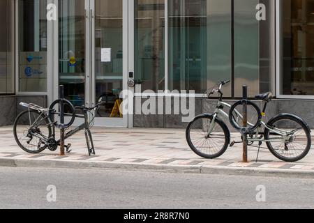 Ottawa, Canada - 19 mai 2023 : vélos garés dans la ville sur le trottoir au porte-vélos. Siège et roue volés d'une seule moto. Banque D'Images