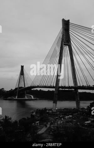 Une capture monochrome captivante d'un point de vue humain, mettant en valeur la présence imposante du pont emblématique de Barelang. Banque D'Images