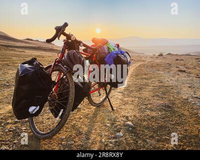 Equipé de sacs, le vélo rouge se dresse sur le côté de la route, entouré de montagnes, dans la campagne du parc national de Vinshlovani. Vacances de vélo à Geo Banque D'Images