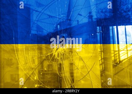 Trou de balle, fissures dans le verre sur fond jaune-bleu. Drapeau de l'Ukraine sur la texture du verre brisé. Concept, guerre russo-ukrainienne. Banque D'Images