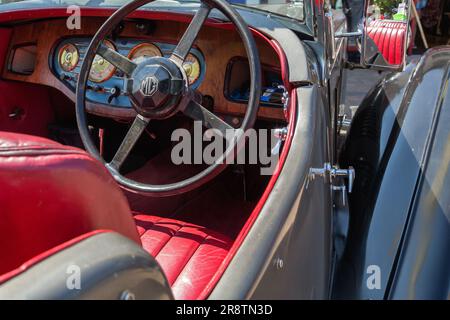 L'intérieur d'un 1930s MG va, avec le logo MG, la planche de bord, le volant et les sièges en cuir rouge. Voiture britannique lors d'un spectacle de voitures classique et vintage. Banque D'Images