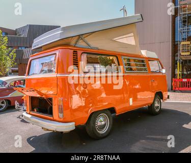 Un camping-car orange Volkswagen des années 1970 avec son toit élévateur relevé. VW camping-car au salon des voitures classiques et anciennes. Banque D'Images