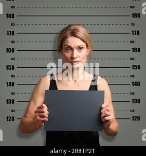 Coup de feu criminel. Femme arrêtée avec une carte vierge contre le tableau de hauteur Banque D'Images