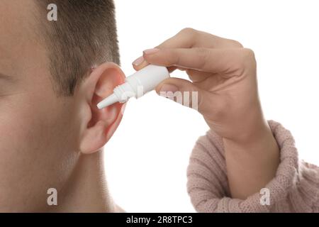 Femme qui goutte des médicaments dans l'oreille de l'homme sur fond blanc, gros plan Banque D'Images