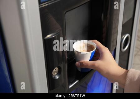 Femme prenant une tasse en papier avec du café du distributeur automatique, gros plan Banque D'Images