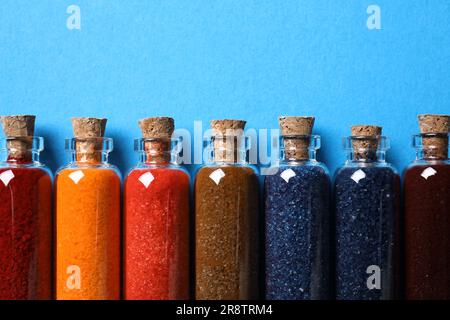 Flacons en verre avec différentes couleurs alimentaires sur fond bleu clair, à plat. Espace pour le texte Banque D'Images