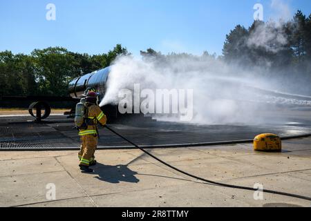 ÉTATS-UNIS Le premier Airman Zach Gager de la Force aérienne et le sergent d'état-major Ronald Card, pompiers de l'escadron de la base aérienne 424th, vaporisent de l'eau sur un simulateur d'incendie d'avion avec des pompiers hollandais de l'escadron 941st, au Centre d'entraînement de secours et d'incendie de la Force aérienne royale des pays-Bas, à Woensdrecht, aux pays-Bas, au 15 juin 2023. (É.-U. Photo de l'armée par Pierre-Etienne Courtejoie) Banque D'Images