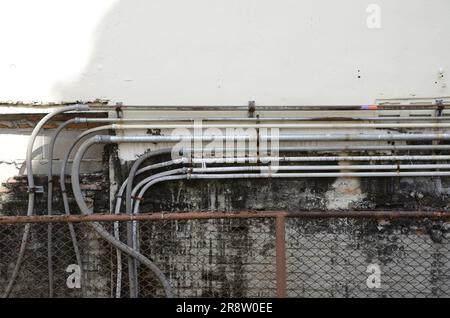 Vue rapprochée de divers conduits électriques montés sur un mur blanc, vu d'un léger angle Banque D'Images