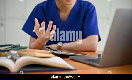 L'image rapprochée d'un étudiant ou d'un médecin spécialisé en médecine masculine dans les exfoliations est d'avoir un examen médical en ligne avec un patient ou de se joindre à un webi médical Banque D'Images