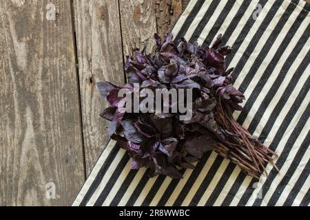 un bouquet de basilic rouge se trouve sur une table en bois dans la cuisine Banque D'Images