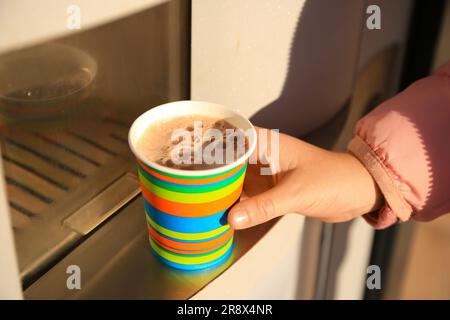 Femme prenant une tasse en papier avec du café du distributeur automatique, gros plan Banque D'Images