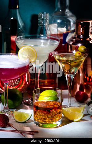 Cocktails alcoolisés, boissons fortes et apéritifs, outils de bar, bouteilles sur fond vert foncé, lumière dure. Martini vodka, dame rose, aperol spritz Banque D'Images