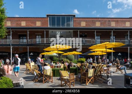 Les personnes assises autour de la nourriture et des boissons au centre commercial Gunwharf Quays à Portsmouth un samedi ensoleillé, Hampshire, Angleterre, Royaume-Uni Banque D'Images