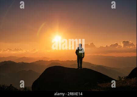 Homme de randonnée réussi en silhouette debout au sommet de la montagne avec le soleil qui brille sur la montagne au coucher du soleil dans le parc national Banque D'Images