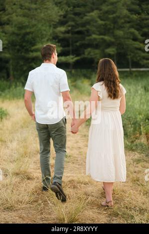jeune couple se tenant les mains et marchant loin dans le parc pittoresque Banque D'Images