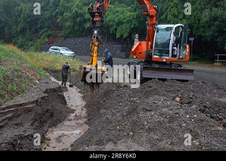 Thale, Allemagne. 23rd juin 2023. Les employés de la cour du bâtiment déblayer une tranchée à Thale. Le lendemain de la tempête, le travail de nettoyage est en plein essor. Dans le district de Harz en particulier, plusieurs villes comme Thale ont été directement touchées par la tempête. À Thale, des masses d'eau ont lavé des tonnes de débris sur une route et dans un fossé. La route était fermée jusqu'à midi. Credit: Matthias Bein/dpa/Alay Live News Banque D'Images