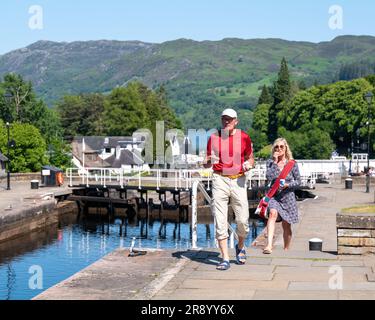 15 juin 2023. Fort Augustus, Écosse. C'est un homme et une femme en vacances au sommet des marches le long des écluses du canal en train de manger de la glace Banque D'Images