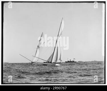 Columbia traversant la ligne, Shamrock I, vers l'arrière, 1899 octobre 7. Columbia était un yacht de course américain conçu et construit en 1898-99 par Nathanael Herreshoff et The Herreshoff Manufacturing Company pour les propriétaires J. Pierpont Morgan et Edwin Dennison Morgan du New York Yacht Club. En 1899, elle a été la défenseuse de la dixième course de la coupe de l'Amérique contre le challenger britannique/irlandais Shamrock. Banque D'Images