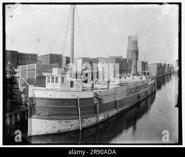 Chargement de bois d'œuvre sur un bateau à vapeur à des cours de bûcherons, Menominee, au Michigan, entre 1880 et 1899. Banque D'Images